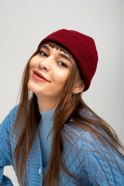 Moda kıyafetleri içinde genç bir kadın neşeli bir poz verir. Sonbahar havasında neşe ve rahatlık saçar..