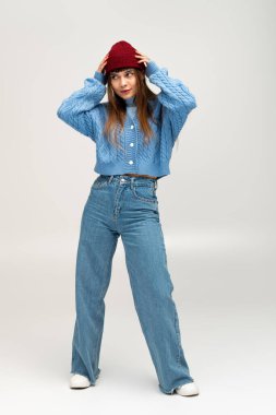 Genç bir kadın şık ve sıcak kıyafetlerini sergiliyor. Keyifli bir ortamda poz veriyor..