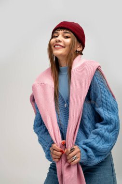 Güzel, genç bir kadın sıcak, şık giysiler içinde, neşe ve rahatlık saçarak poz verir..