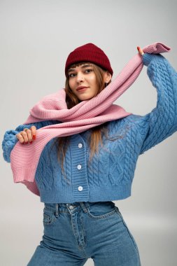 Rahat giysiler içindeki genç kadın, sonbaharın sıcağını kucaklayan bir eşarpla neşe içinde poz veriyor..