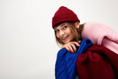 Güzel, genç bir kadın parlak bir şekilde gülümser. Renkli, rahat bir elbiseye bürünmüş, sıcacık bir şekilde..