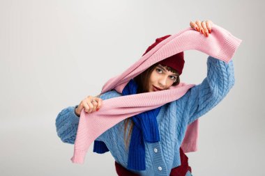 Güzel genç bir kadın, hoş bir sonbahar elbisesi içinde renkli eşarplar sergileyerek vakit geçirmekten zevk alıyor..