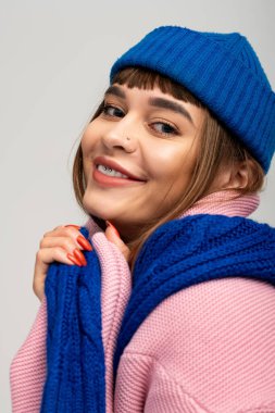 Sıcak giyimli genç kadın, sonbaharda rahat kıyafetinin rahatlığını kucaklayarak ışıl ışıl gülümsüyor..