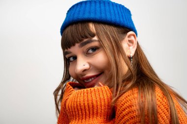 Güzel, genç bir kadın sıcak bir şekilde gülümsüyor, şık kış kıyafetlerini ve neşeli tavırlarını sergiliyor..