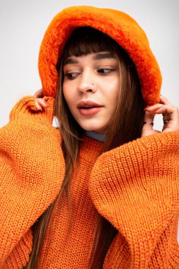 Güzel, genç bir kadın rahat turuncu giysiler içinde, sıcak ve tarz dolu pozlar veriyor..