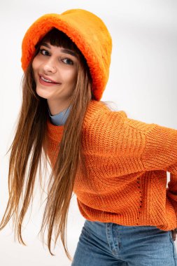 Güzel genç bir kadın, sonbahar mevsimini kucaklayan, sıcak turuncu giysiler içinde neşeli bir şekilde poz verir..