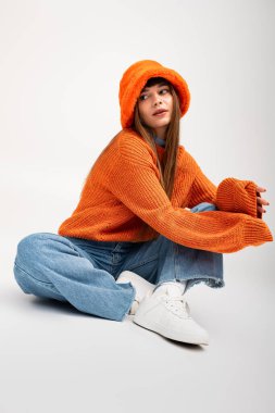 Sıcak turuncu elbiseli güzel bir kadın rahat bir ortamda tarz ve kendine güvenle poz verir..