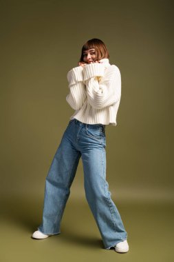 Güzel, genç bir kadın sıcak ve şık giysiler içinde, sonbahar havası ve neşe saçan pozlar veriyor..