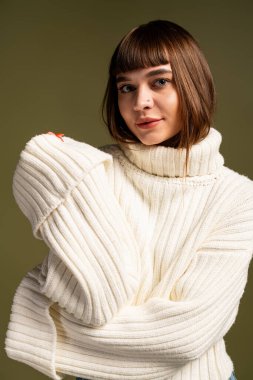 Güzel, genç bir kadın rahat bir şekilde poz verir. Sıcak kıyafetler giyer, sonbahar atmosferini kucaklar..