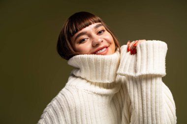 Şık, sıcak giysiler içinde genç bir kadın mutluluk dolu pozlar veriyor, sıcaklığı ve güveni yayıyor..