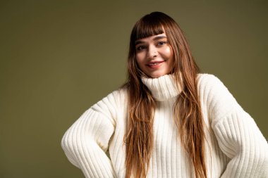 Güzel genç bir kadın sıcacık giysiler içinde poz verir, sonbahar aylarında sevinç saçar..