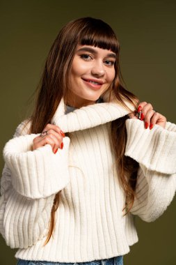 Neşeli genç kadın, zengin bir zemin karşısında sıcak bir şekilde poz veriyor, neşe ve tarz yayıyor..