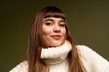 Güzel, genç bir kadın rahat bir şekilde poz verir, serin bir günde sıcaklık ve güven saçar..