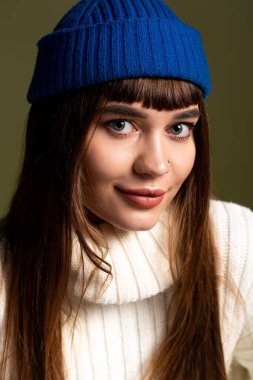 Güzel genç bir kadın aktif olarak poz veriyor, yumuşak bir zemine karşı sıcak kıyafetlerini sergiliyor..