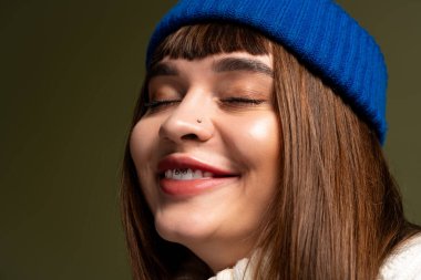 Güzel genç bir kadın, rahat bir kıyafet giyerek, güz havasının sıcaklığını yakalayarak neşeyle gülümsüyor..