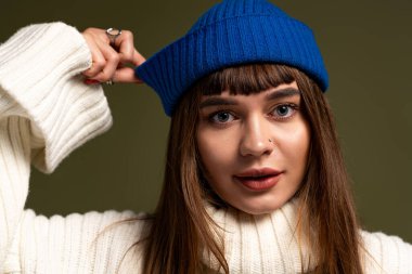 Güzel, genç bir kadın sıcak ve şık bir sonbahar havası uyandıran, kendine güvenen bir şekilde poz verir..