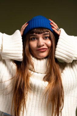 Sıcak giyimli genç kadın, sonbahar ve kış modasının güzelliğini kucaklayarak neşe içinde poz veriyor..