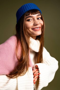 Genç bir kadın sıcak, renkli giysiler içinde poz verirken neşe saçıyor, serin günler için mükemmel..