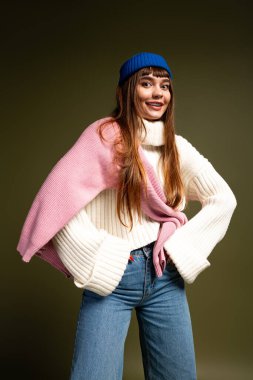 Güzel, genç bir kadın şık, sıcak giysiler içinde, neşe ve güven saçarak poz veriyor..