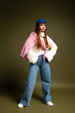 Güzel genç kadın enerjik bir şekilde poz veriyor, serin mevsim için sıcaklığı ve stili somutlaştırıyor..