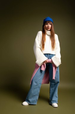 Genç kadın, serin mevsimlerde sıcacık sonbahar modasına bürünmüş, sıcaklığı ve tarzı somutlaştıran bir cazibe sergiliyor..