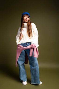 Güzel genç bir kadın rahat ve şık bir sonbahar kışı elbisesi içinde sıcak bir şekilde poz verir..