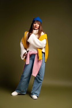 Genç bir kadın rahat bir şekilde poz verir, sonbahar tarzının ve sıcaklığın özünü yakalar..