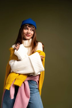 Genç bir kadın rahat, şık giyinmiş, sonbahar havasını somutlaştıran bir şekilde poz verir..