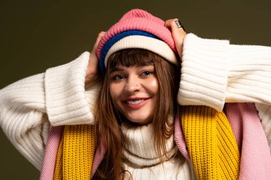 Genç kadın sıcak, modaya uygun giysiler içinde mutlu poz veriyor, sonbaharda neşe saçıyor..