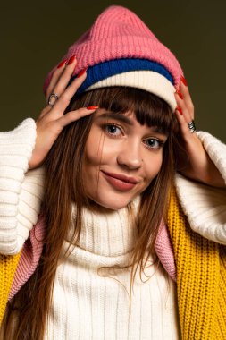 Şık bir sonbahar kıyafeti ve canlı bir şapkayla poz verirken genç kadınların yüzünde parlak bir gülümseme.