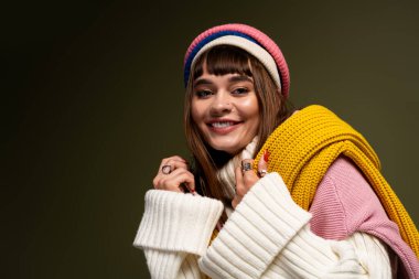 Parlak giyimli genç bir kadın, neşeli bir şekilde poz verirken rahat örgü giysilerinin sıcaklığından zevk alır..