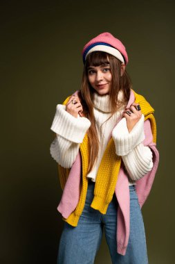 Kendine güvenen genç bir kadın şık, sıcak kıyafetler, ışık saçan cazibe ve enerjiyle poz verir..