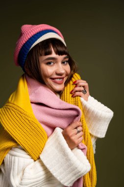 Neşeli genç kadın katmanlı eşarplarla poz veriyor, sonbahar mevsiminin sıcaklığını kucaklıyor..