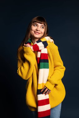 Neşeli genç bir kadın sıcak, şık bir sonbahar elbisesi içinde poz verir, sahneye neşe katar..