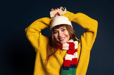 Parlak elbiseli bir kadın ve neşeli bir gülümseme sonbahar ve kış kıyafetleri sergiler..