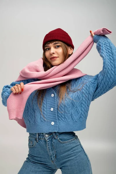 Rahat giysiler içindeki genç kadın, sonbaharın sıcağını kucaklayan bir eşarpla neşe içinde poz veriyor..