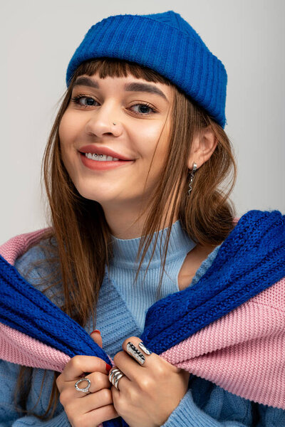 A beautiful young woman with long hair joyfully poses in vibrant layers of stylish clothing.