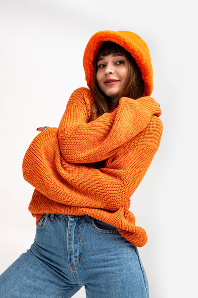 Молодая женщина излучает радость в стильном осеннем наряде с ярко-оранжевой толстовкой и теплой улыбкой.