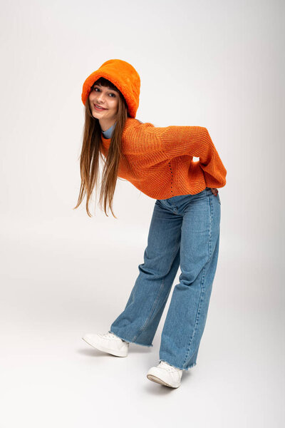 Молодая женщина игриво позирует в теплой, стильной одежде, излучая радость осенью.