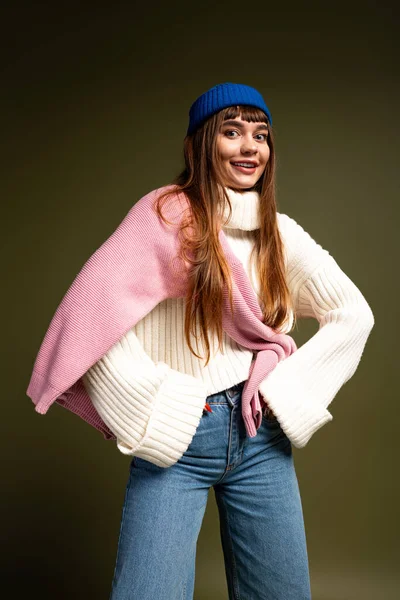 Güzel, genç bir kadın şık, sıcak giysiler içinde, neşe ve güven saçarak poz veriyor..