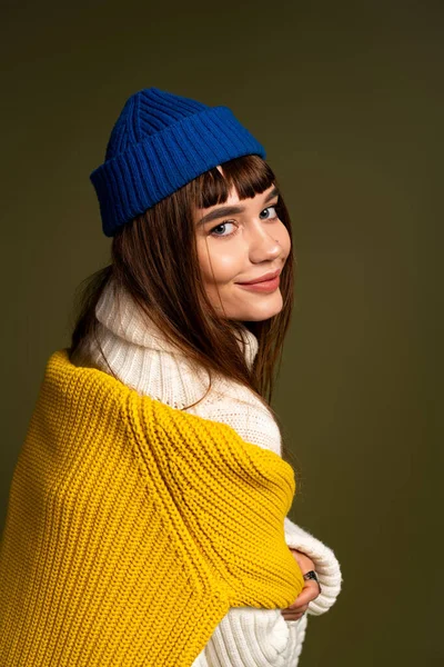 Genç bir kadın renkli kışlık giysiler içinde, sıcak ve neşe saçan pozlar veriyor..