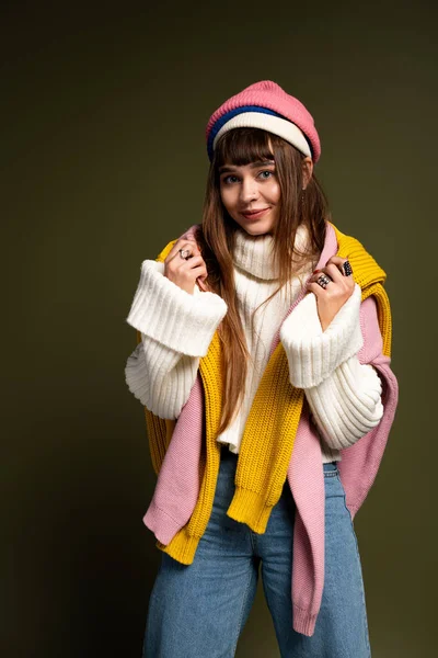 Kendine güvenen genç bir kadın şık, sıcak kıyafetler, ışık saçan cazibe ve enerjiyle poz verir..