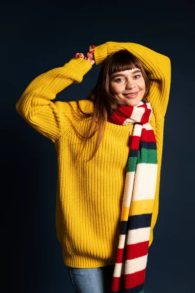 Çekici genç kadın, sonbahar sezonunu kutlamak için rahat bir kazak ve eşarpla poz veriyor..