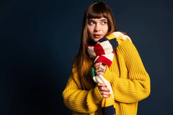 Güzel bir kadın, sonbaharda neşe içinde poz verirken sıcak elbisesini neşeli bir eşarpla sergiliyor..