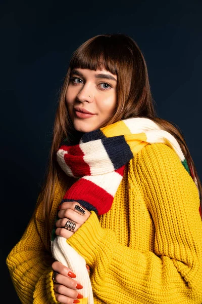 Genç kadın rahat, renkli giysiler içinde serin mevsimlere hazır bir şekilde poz veriyor..