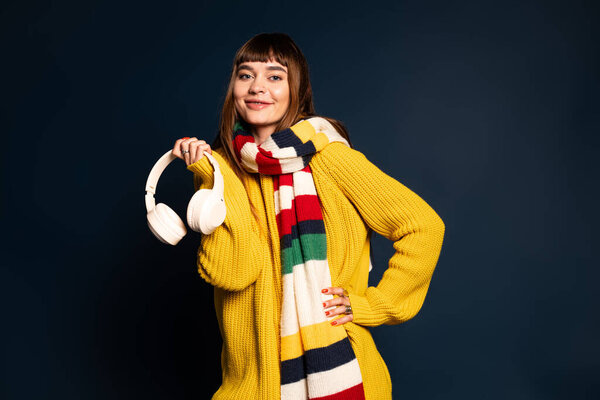 Красивая молодая женщина радостно позирует в теплой стильной одежде, излучая уверенность и комфорт.