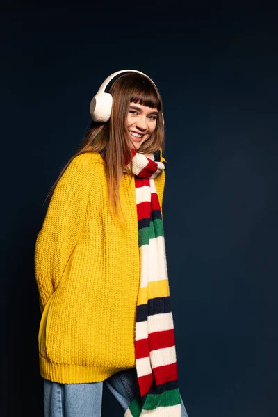 Güzel genç bir kadın renkli kış giysileri içinde mutlu bir şekilde poz verir, sıcaklık ve neşe saçar..