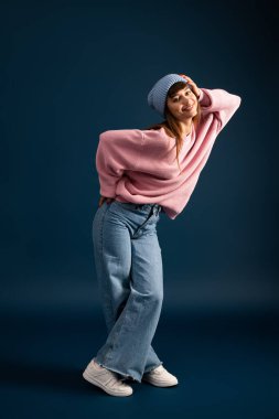 Güzel, genç bir kadın, güz mevsimini yansıtan sıcak ve şık giysiler içinde poz verir..