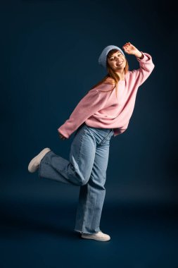 Sıcak, şık giyinmiş genç bir kadın, mevsimin neşesini gösteren neşeli bir poz verir..