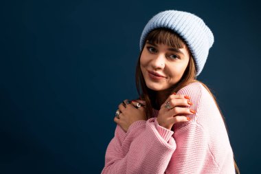 Genç bir kadın sıcak ve şık elbisesiyle neşe ve rahatlık saçarak poz veriyor..